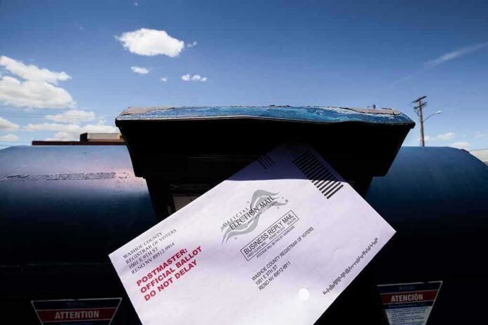 shutterstock_1789887014 Mail-in ballot being inserted into a blue USPS mailbox