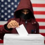 DOJ Bust Exposes Election-Immigration Trap Voter in hood and mask casting ballot into box