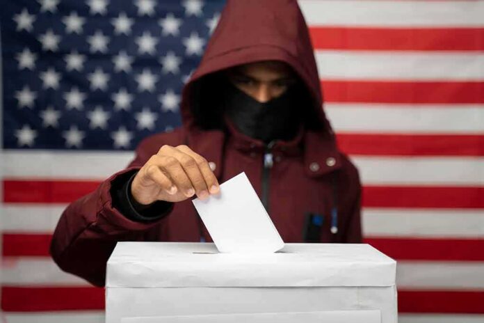 shutterstock_1830585293 Voter in hood and mask casting ballot into box
