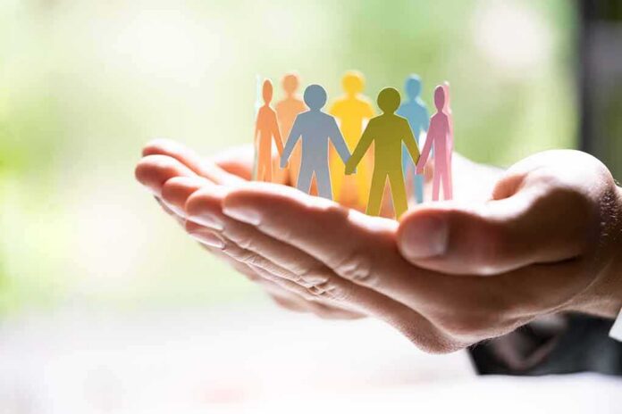 shutterstock_2009312513 Hands holding a row of colorful paper people