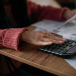 Person using a calculator with bills on a desk