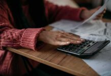 Financial Stress Remains Alarmingly High Person using a calculator with bills on a desk