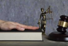 Washington Faces Trump’s Merit Test Hand on a book with gavel and Lady Justice statue