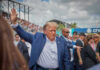 Rally Chaos Explodes In North Carolina Person in blue suit waving at outdoor event.