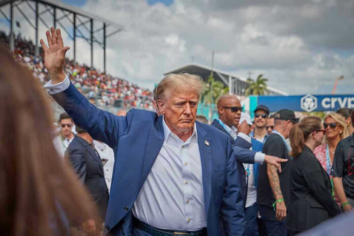 2458373881-2 Person in blue suit waving at outdoor event.