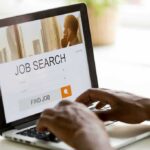 Hands typing on laptop with job search website open