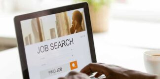 Hands typing on laptop with job search website open