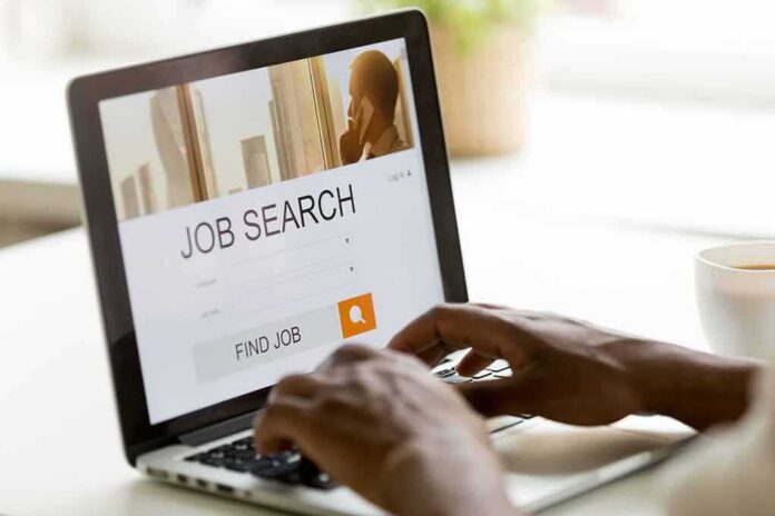 Hands typing on laptop with job search website open