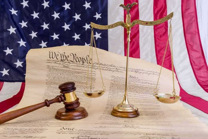 Scales of justice and gavel on the U.S. Constitution with American flag backdrop