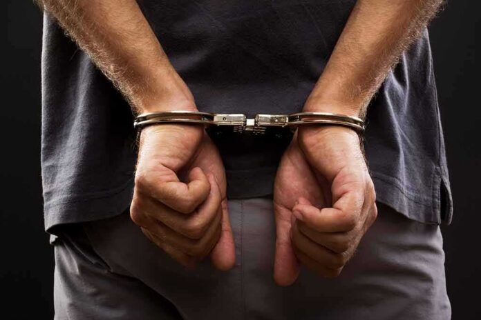 person with hands cuffed behind back