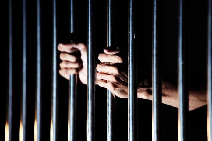 shutterstock_1135369001 hands gripping prison bars