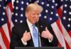 Donald Trump speaking at a podium with American flags behind him