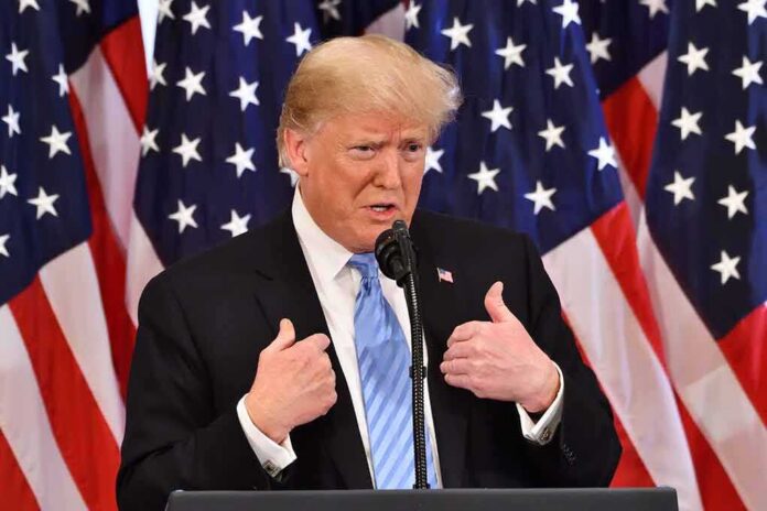 Donald Trump speaking at a podium with American flags behind him