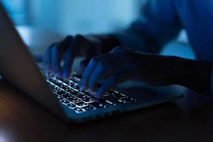Hands typing on a backlit laptop keyboard at night