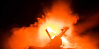 Toy helicopter silhouette against fiery explosion at night
