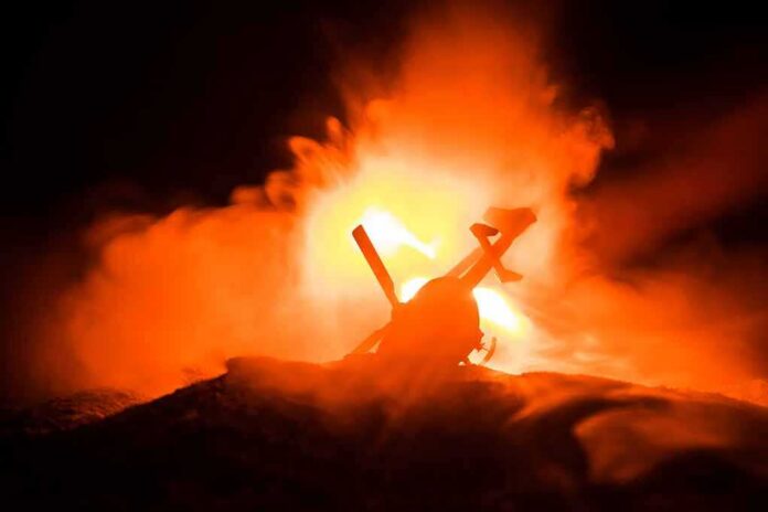 shutterstock_1220566891 Toy helicopter silhouette against fiery explosion at night