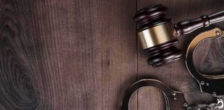 Judge’s gavel and metal handcuffs on wooden table