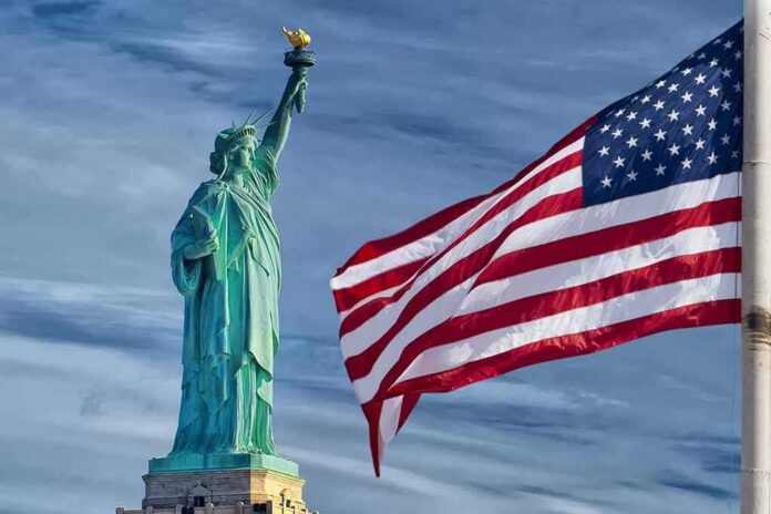 shutterstock_137771480 Statue of Liberty beside a waving American flag