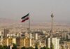 Invisible Leader Claims Grip On Iran Iranian flag over Tehran skyline with Milad Tower