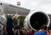Group of people gathered near a large airplane engine