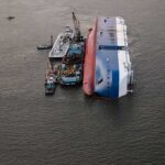 Capsized cargo ship with salvage vessels alongside