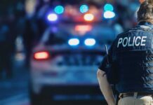 Counter-Terror Cordon Around US Air Hub police officer in vest near patrol car with flashing lights