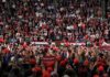 Speaker at podium addressing large crowd in arena