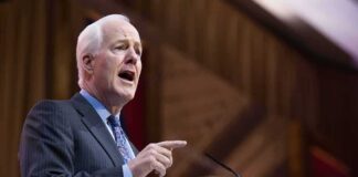 Elderly man in suit speaking at a podium