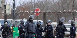 Group of police officers in riot gear standing on a street; Brian Folkerts present