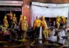 Citywide Inferno Tied To Encampments Firefighters work outside a damaged warehouse with debris and hoses