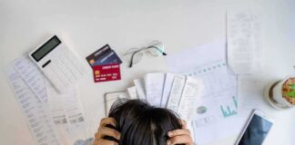 Person holding head over bills and credit cards on desk