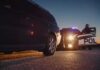 Police officer at patrol car during traffic stop at dusk