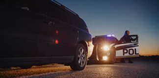 Police officer at patrol car during traffic stop at dusk