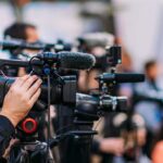 DSA Pushes Sweeping Constitutional Overhaul Video cameras on tripods at a media event