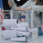 Shock Win Triggers Identity Brawl Person casting a ballot into a clear box at a polling station
