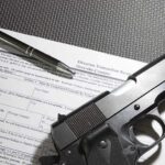 Handgun on firearm transaction form with pen