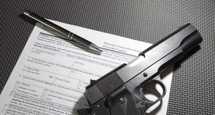 shutterstock_581003293 Handgun on firearm transaction form with pen