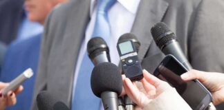 Microphones held toward a person in a suit