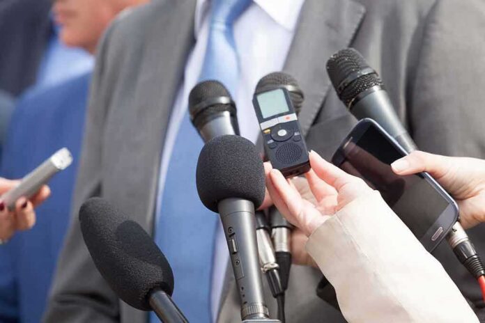 shutterstock_618881507 Microphones held toward a person in a suit