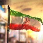 Iranian flag waving on a pole at sunset
