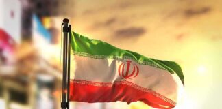 Iranian flag waving on a pole at sunset