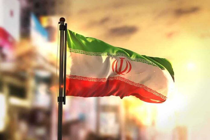 Iranian flag waving on a pole at sunset