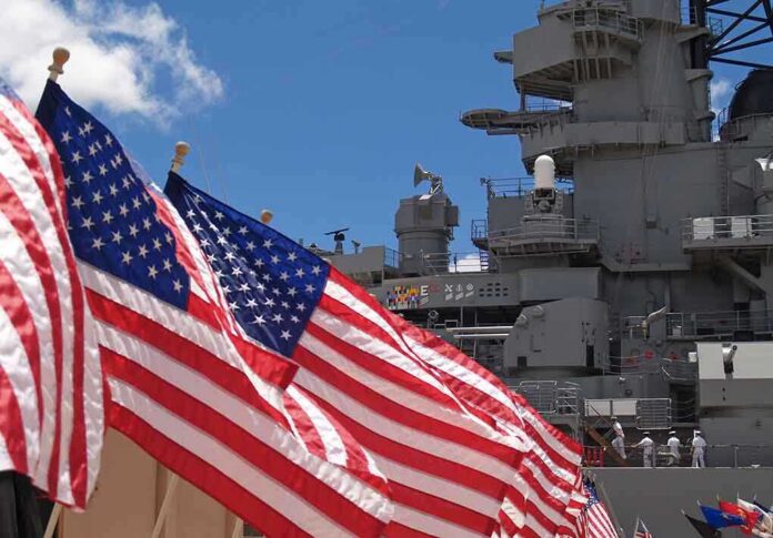 shutterstock_64270615 American flags in front of a naval ship under a blue sky