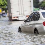 Silver car partially submerged in floodwater