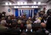 White House Purge Ignites Press War Press secretary at podium addressing reporters in briefing room
