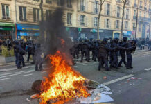 Fire burning on the street amid police presence.