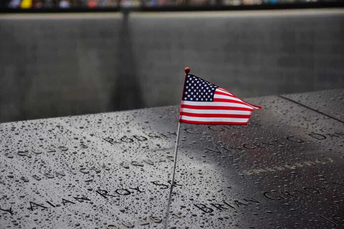 574569265 American flag on a rainy memorial nameplate.