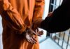 Celebrity Arrest Leads To Court Order Prisoner in orange jumpsuit handcuffed by officer