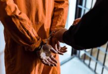 Celebrity Arrest Leads To Court Order Prisoner in orange jumpsuit handcuffed by officer