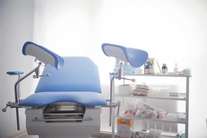 shutterstock_1066517525 Gynecological exam chair with blue padding in a clinic room
